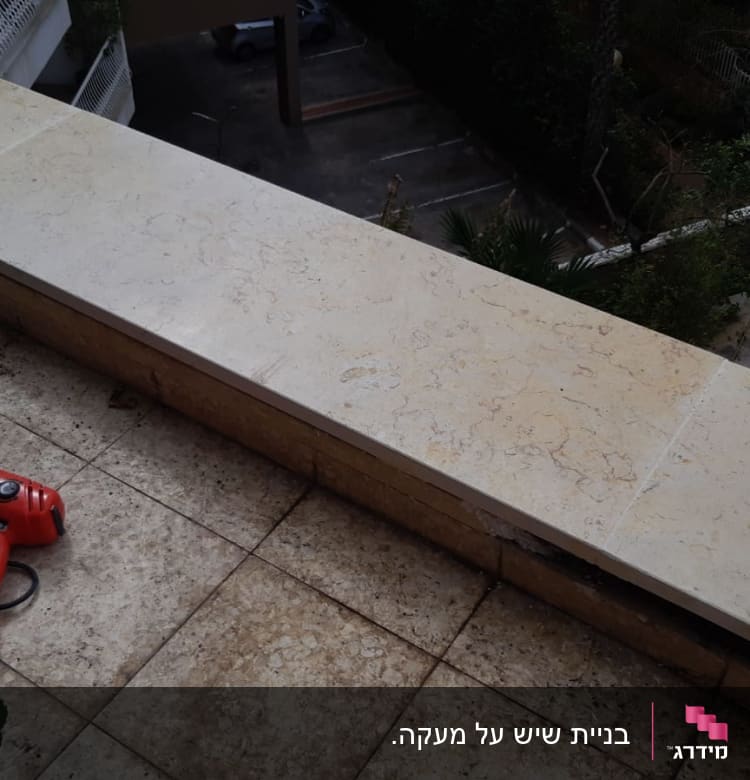 משטח שיש בהיר עם כלי עבודה אדום מונח עליו